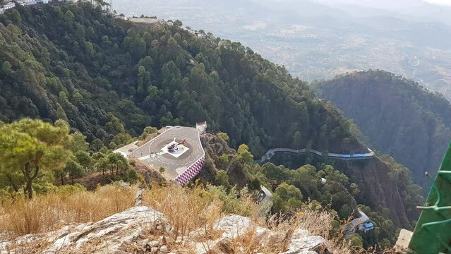 Passengers near a helicopter on a helipad in mountains