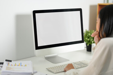 Businesswoman sitting in front of blank screen computer and typing on the keyboard