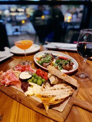 Vertical closeup shot of an Italian dinner with a meat and cheese platter and drinks