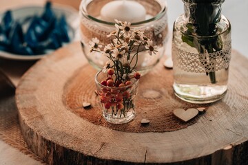 Closeup of a candle and a vase with flowers on a decorative tree stump on a table