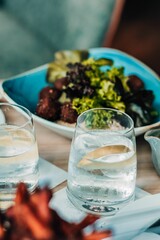 Glasses of ice water against a blurred salad background