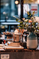 Vertical closeup of a vase with flowers on a table with different equipment. Restaurant interior.