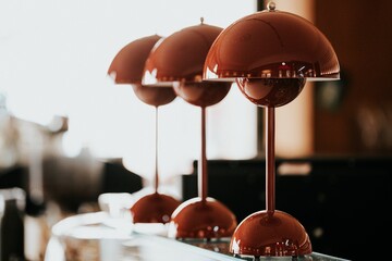 Closeup of a row of dark reddish table lamps.