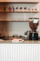 Piece of cake on the bar in a cafe, with a coffee grounding machine and shelves in the background