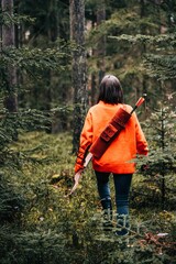 Closeup of a female with a bow and arch walking in the forest