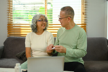 Caring senior husband helping his wife checking blood sugar level at home. Health care concept