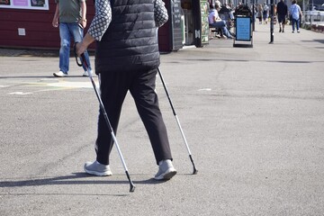 An adult woman with Scandinavian sticks on the street. Active lifestyle in old age