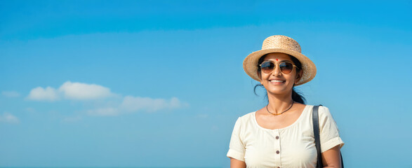 Happy Adult Indian Tourist Woman Wears a Beach Hat Against Blue Sky. Travel Concept.
