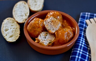 meatballs with sauce in a clay pot with slices of bread