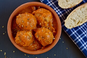 meatballs with sauce in a clay pot with slices of bread