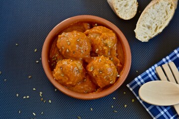 meatballs with sauce in a clay pot with slices of bread