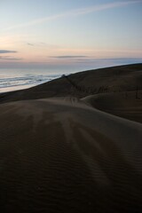 Image of a brown sand on the coast of the sea under the red sunset sky.