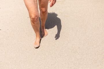 feet of attractive mature woman walking at the beach with full body shadow i