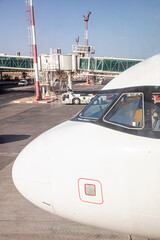 nose of modern jet aircraft in front of the airport terminal