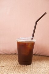 Vertical shot of a coffee cup with a black straw on a pink background