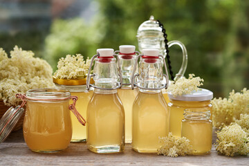 Bottles and jars of homemade elderberry flower syrup outdoors