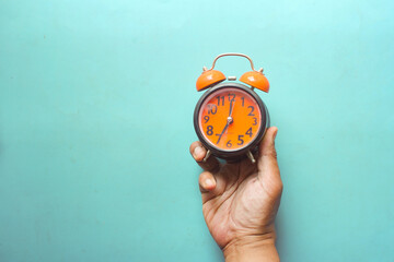  man hand holding alarm clock color background ,