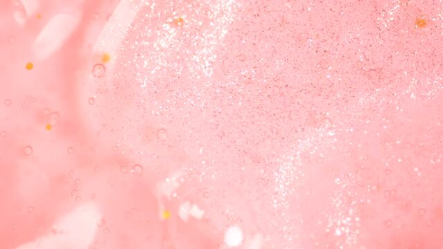 Shimmering body oil pouring in gel fluid. Cosmetics shower gel in peach fuzz color flowing on surface.