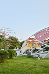 Vertical shot of a children's playground and a kid sitting on the grass and looking forward
