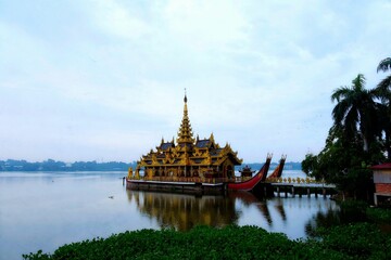 Traditional Asian architecture palace on a floating ship at the shore of Kandawgyi Lake