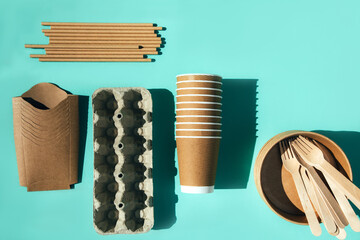 A paper utensils, plates and wooden cutlery on a blue background. Eco friendly pattern, zero waste...