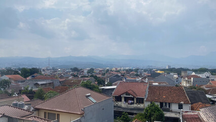 A view of houses residential area in bandung with cloudy sky and a mountain in the background