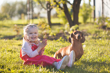 little girl with her dachshund dog in the summer garden