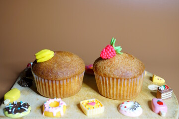 Sweet muffin decorated with raspberries and banana on a brown background.