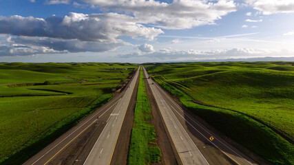 Highway in the middle of a picturesque green field and sky. View from above. Drone photo