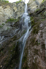 Waterfall hidden inside the forest, beauties of Slovenia to be discovered. Near Nova Gorica, Tolmin village. Water spray and vivid rainbow forms from the waterfall that falls sheer onto the rock.