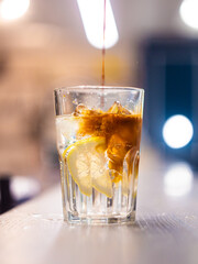 espresso is poured into a glass with ice, lemon and tonic in a thin, high stream. Espresso tonic. Making lemonade. on the bar counter, blurred background

