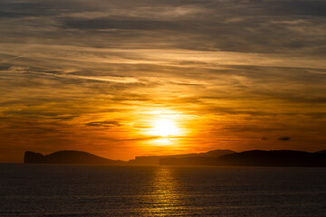 Sun goes down behind Capo Caccia in the north of Sardinia, Italy