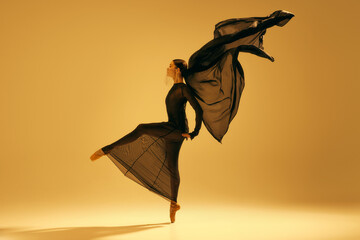 Dynamic ballet movement. Full-length image of artistic female ballet dancer, ballerina in black...