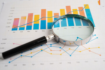 Magnifying glass on spreadsheet and graph paper. Financial development, Banking Account, Statistic,...