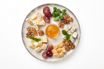 Cheese platter with honey, grape and walnuts on plate