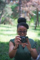 A beautiful black woman taking photos in the park with a camera