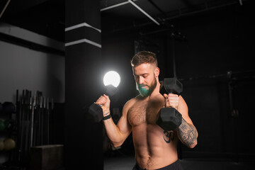 Portrait of man holding dumbells in both hands. Routine workout for physical and mental health.