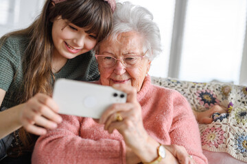 Grandmother with cute girl taking selfie with smartphone. Portrait of an elderly woman spending...