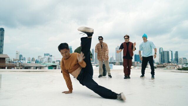 Professional break dance team practice B-boy dance while multicultural friends at rooftop. Young modern dancing group doing hip hop movement. Style,fashion,action. Outdoor sport 2024. Endeavor.