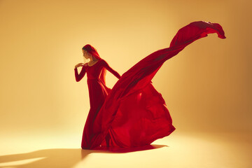 Passion in motion. Beautiful woman, dancer in flowing elegant red dress making powerful performance...