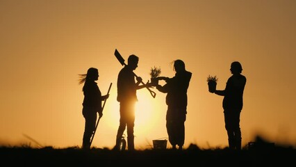 A group of farmers chatting in a field at sunset. With them their work equipment and seedlings