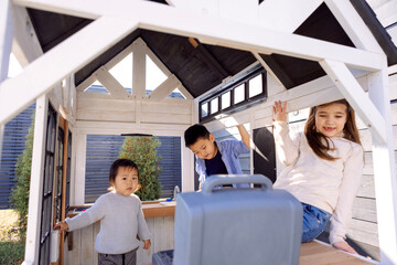 Three small children of different races are playing in a wooden children house. Asian and Caucasian...
