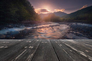Fast mountain river flowing with empty wooden batten bridge. Natural template landscape