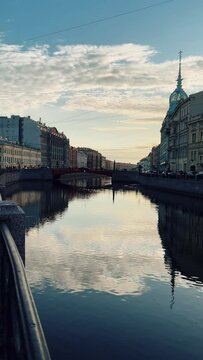Russia, April 09, 2024: The channel in St. Petersburg in the spring. Bridges and historical buildings on the river embankment, people walking along the embankment. Reflections of houses in the water. 