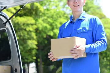 屋外で荷物を運ぶ配送ドライバーの男性
