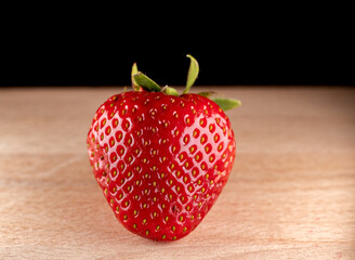 appetizing strawberry on a wooden table and black background