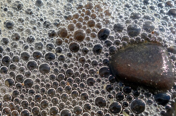 Close-up shot of foam bubbles by the lake shore