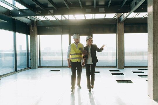 two architect engineers are walking in a constructed office building.