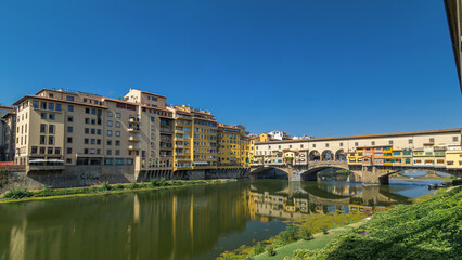 Obraz premium The Ponte Vecchio on a sunny day timelapse hyperlapse, a medieval stone segmental arch bridge over the Arno River, in Florence, Italy