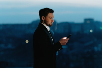 Businessman use smart phone at night in office. A man with a phone in his hands